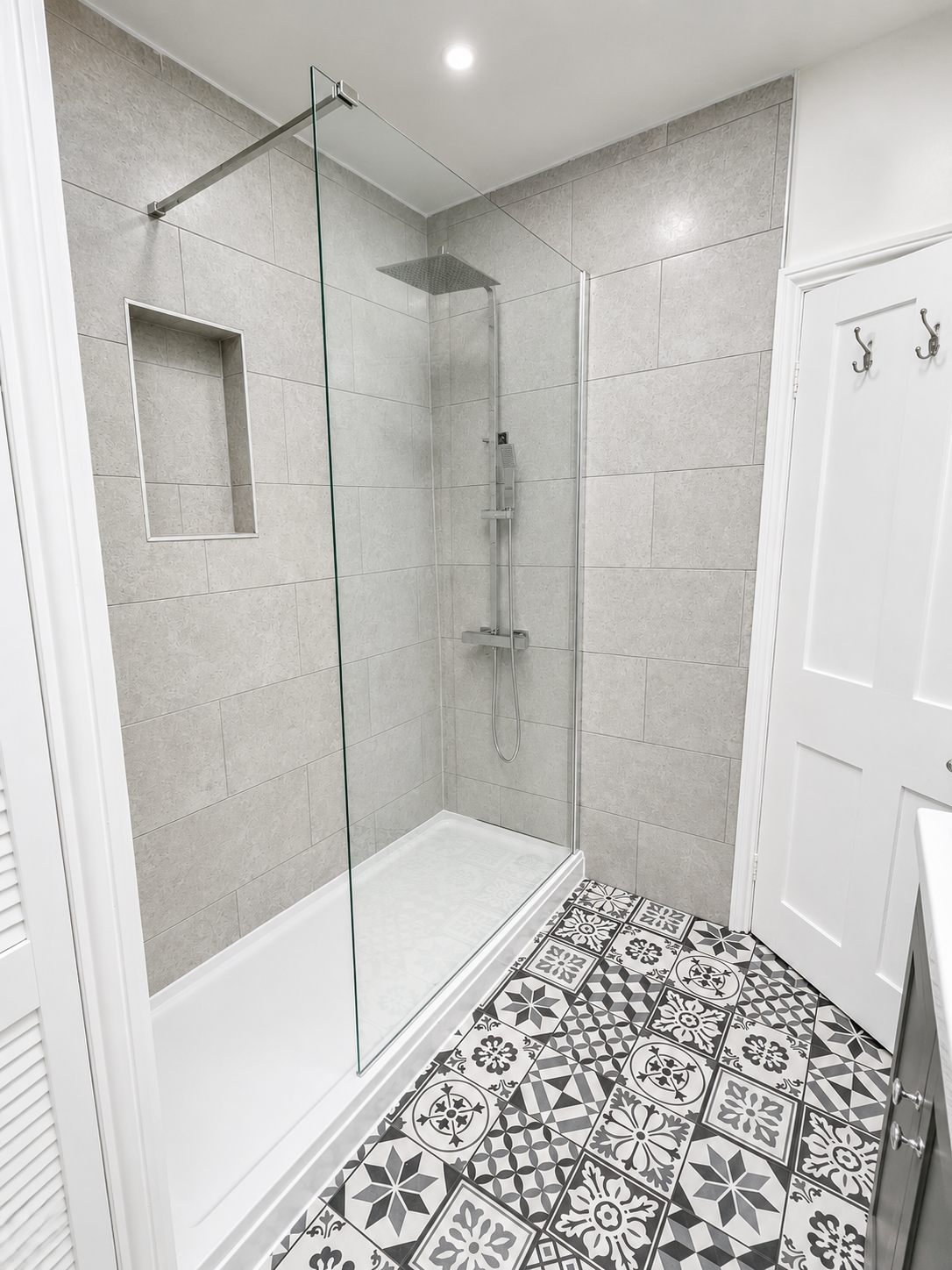 Walk-in shower with clear glass screen and large grey wall tiles