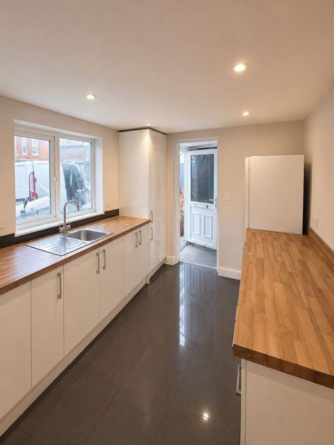 Completed galley kitchen with white cabinets, timber worktops and dark tiled floor