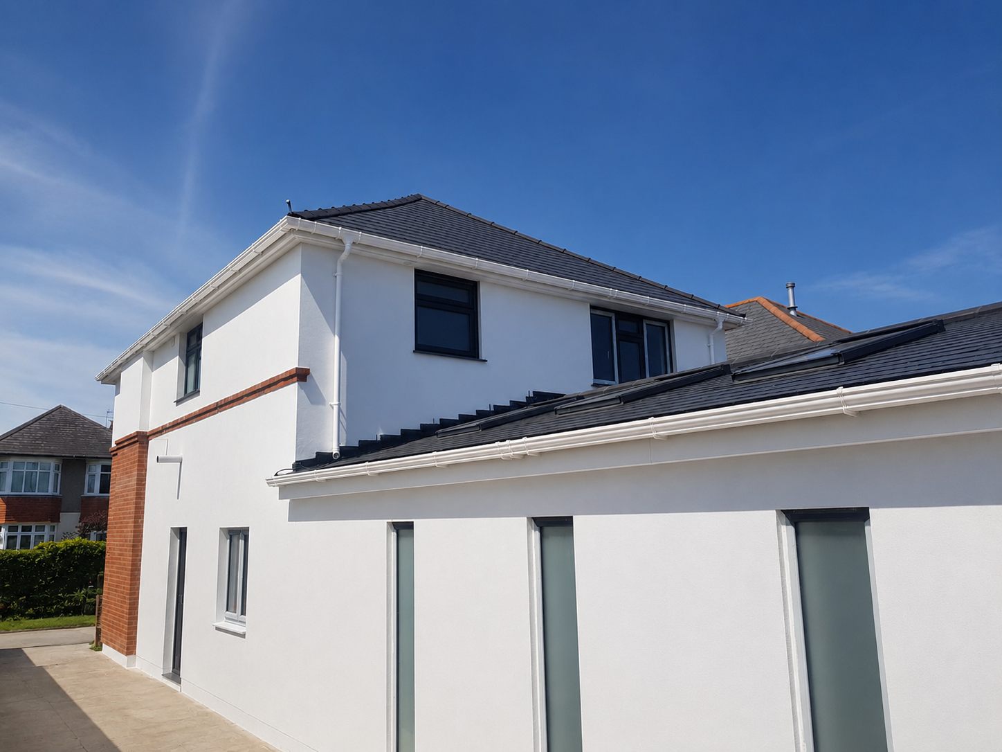 White rendered house exterior with dark roof and windows